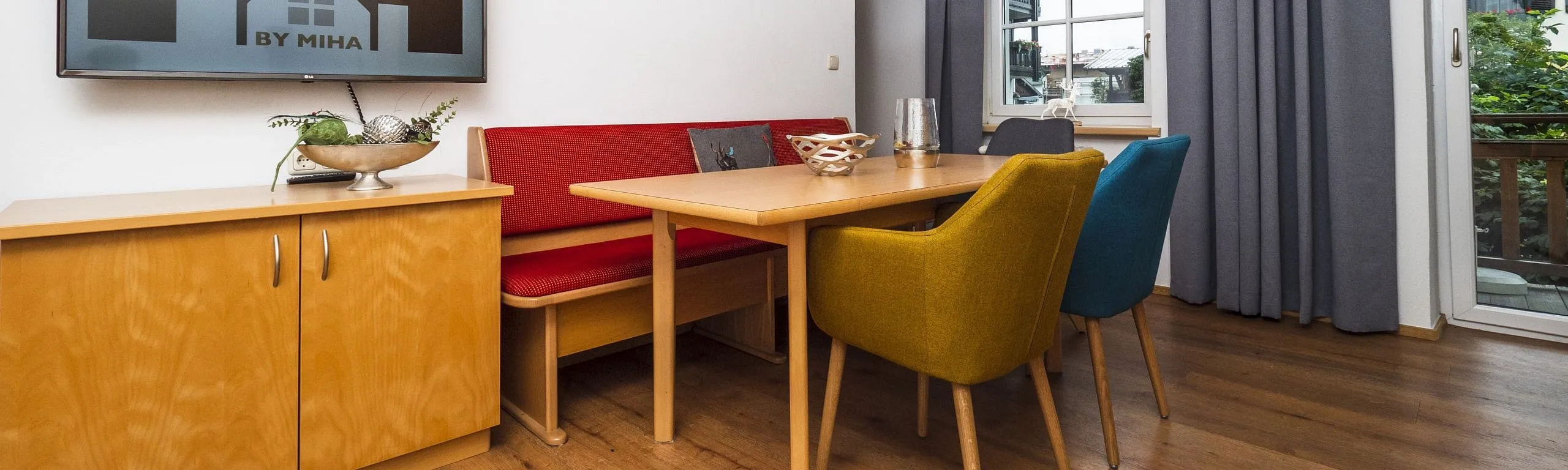 Moderner Essbereich mit Holzmöbeln und bunten Stühlen