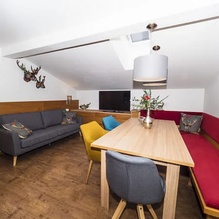 Gemütlicher Wohnbereich mit einem grauen Sofa, roter Sitzgelegenheit und Holztisch.