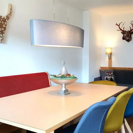 Wohnzimmer mit rotem Sofa, blauem Sessel und dekorativen Geweihen an der Wand