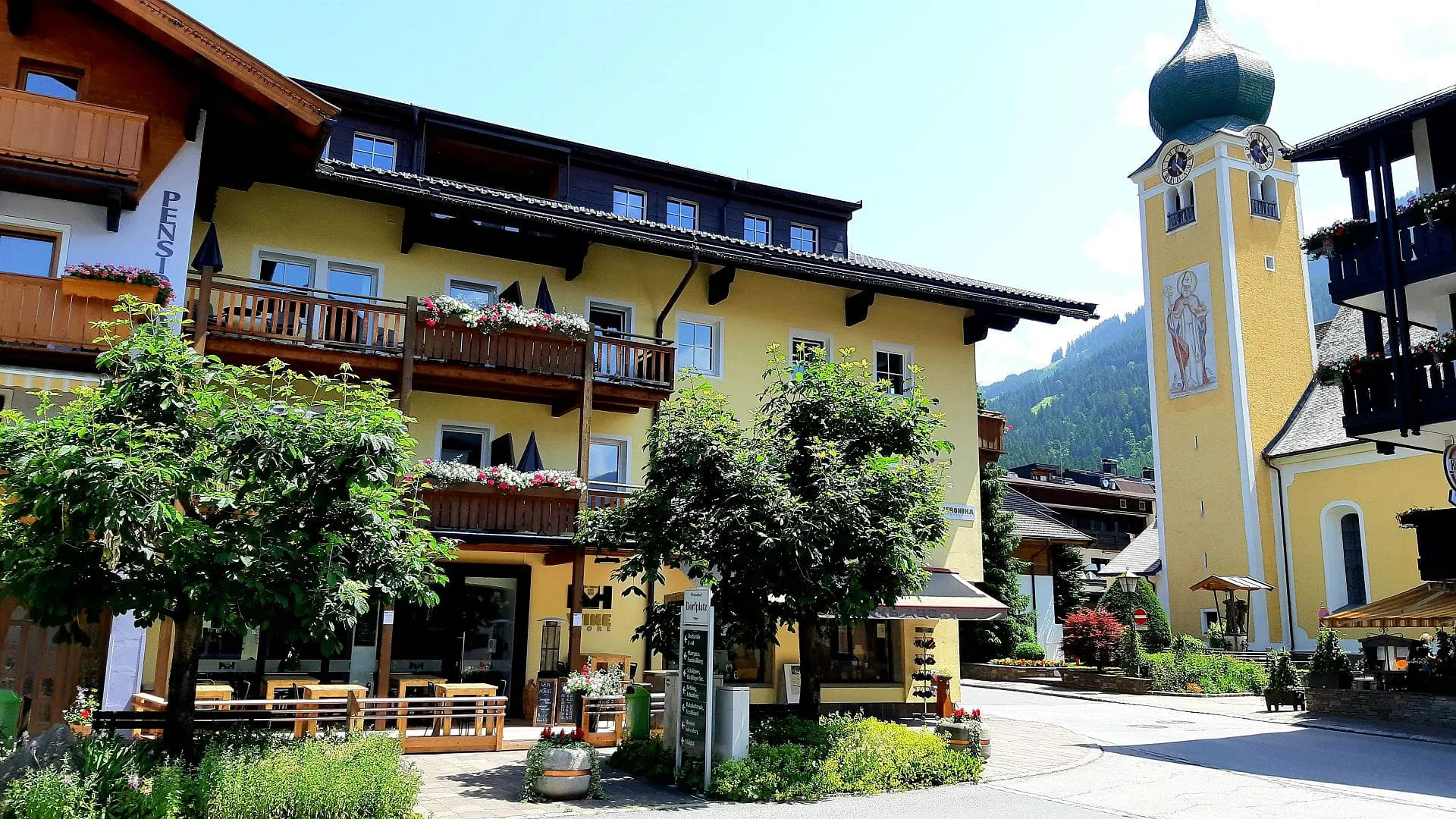 Gelbes Gebäude mit Balkonen und Kirchturm im Hintergrund